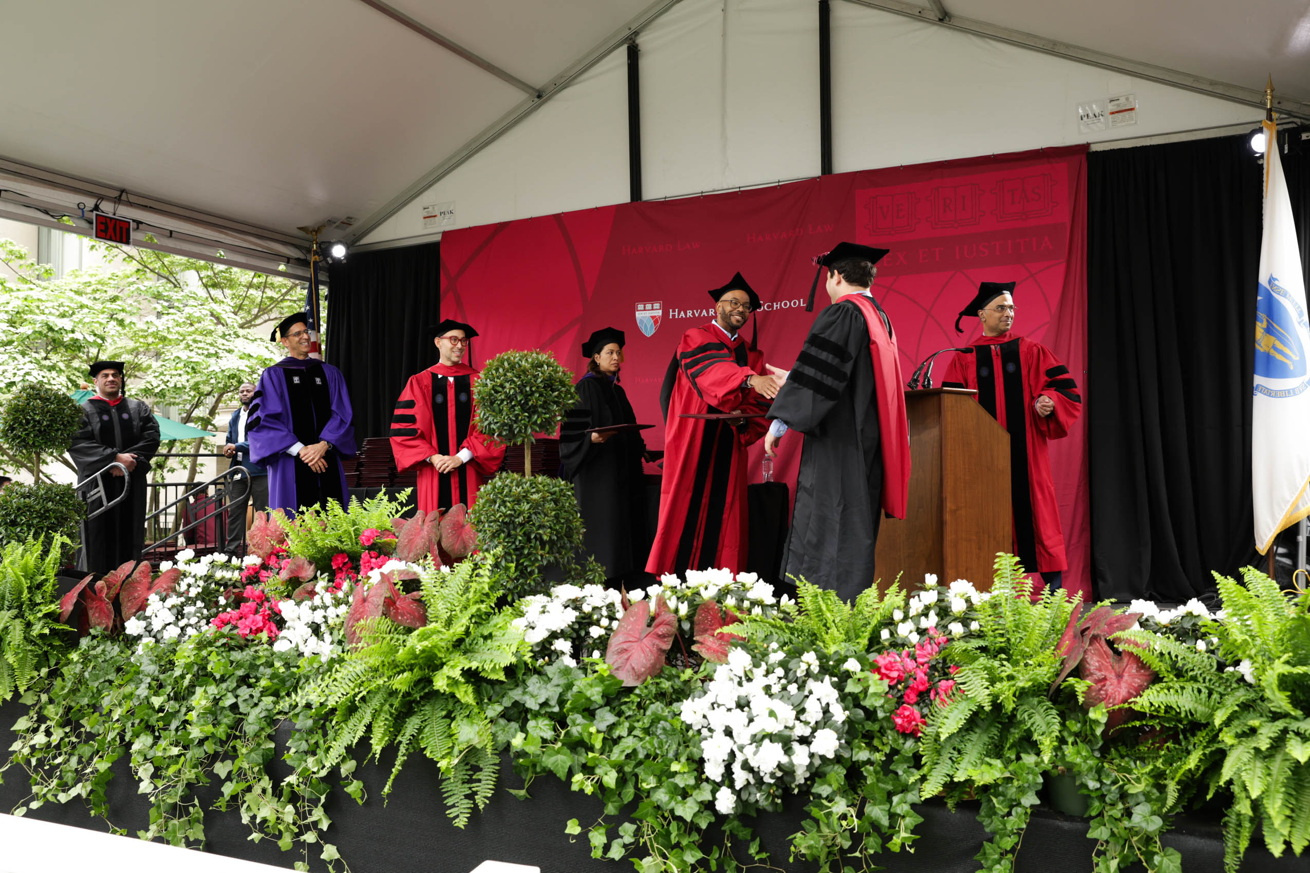 A graduate on stage, shaking hands and receiving his diploma