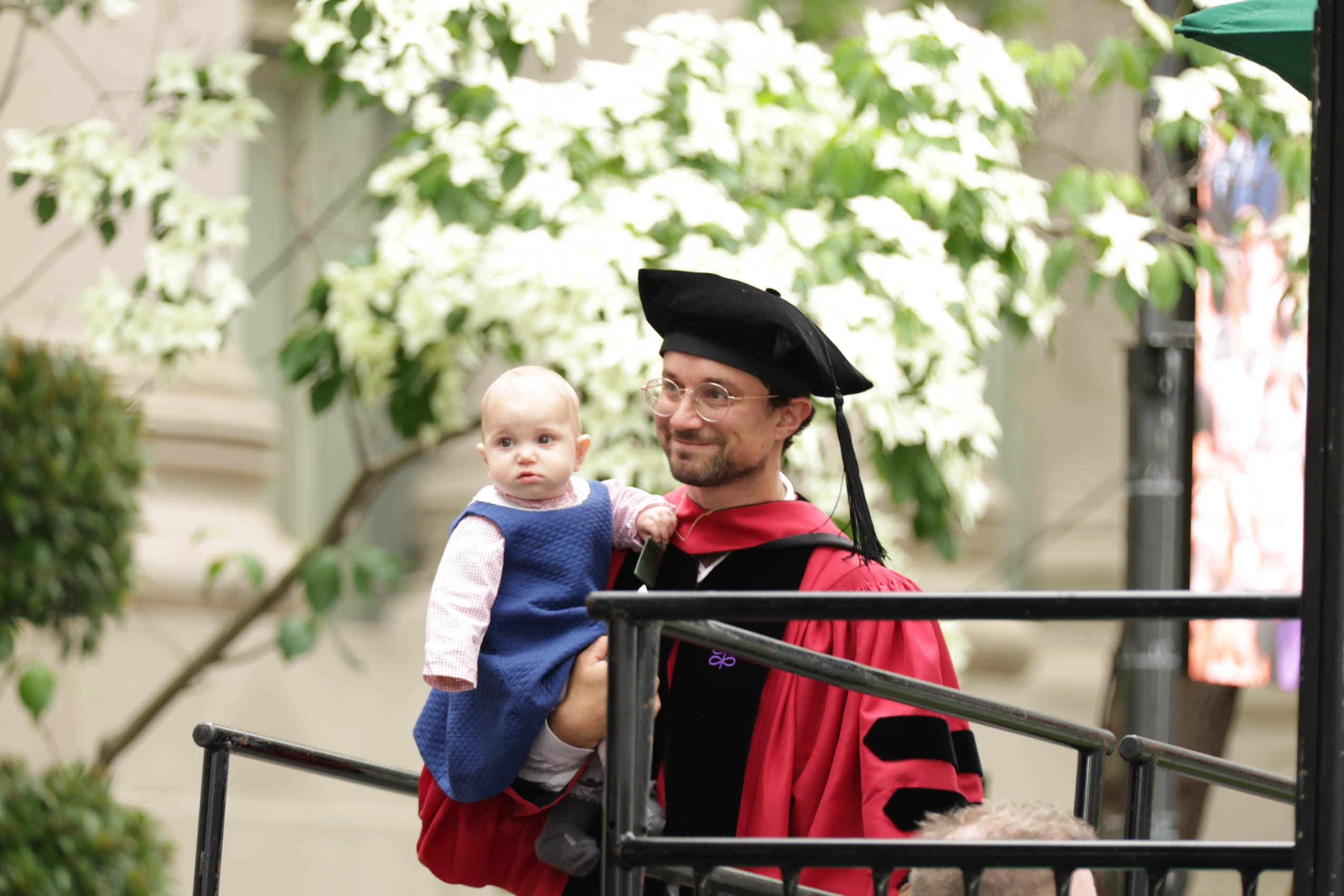 A graduate holding his baby.