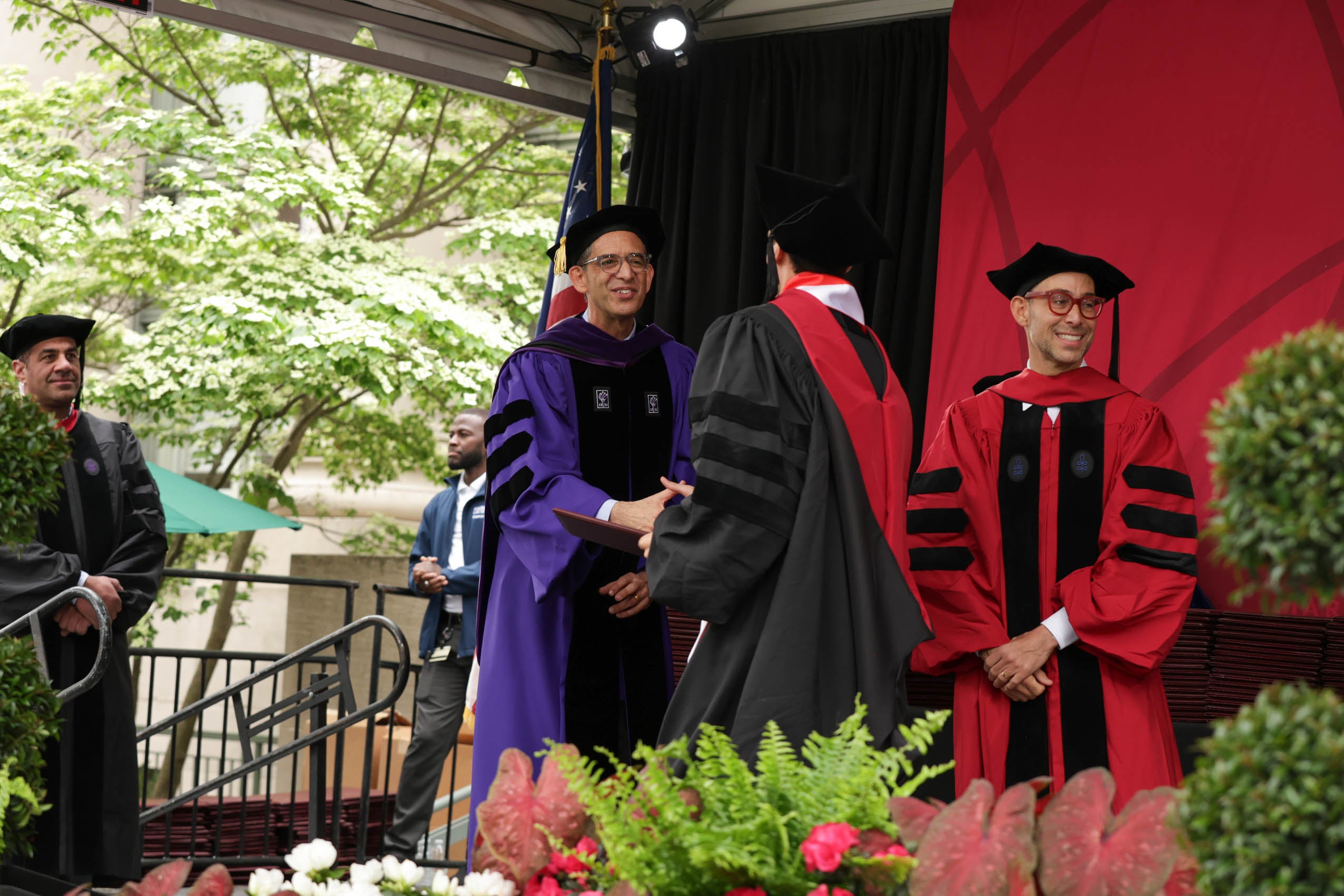 A graduate shaking hands with John Goldberg