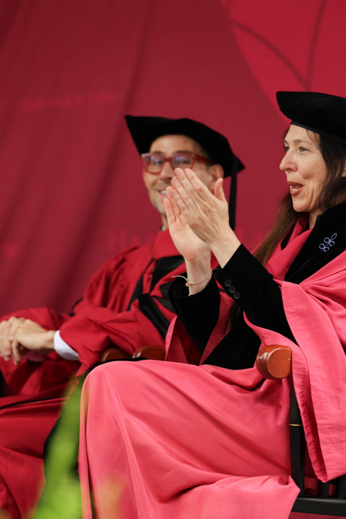 Faculty members sitting on stage and applauding