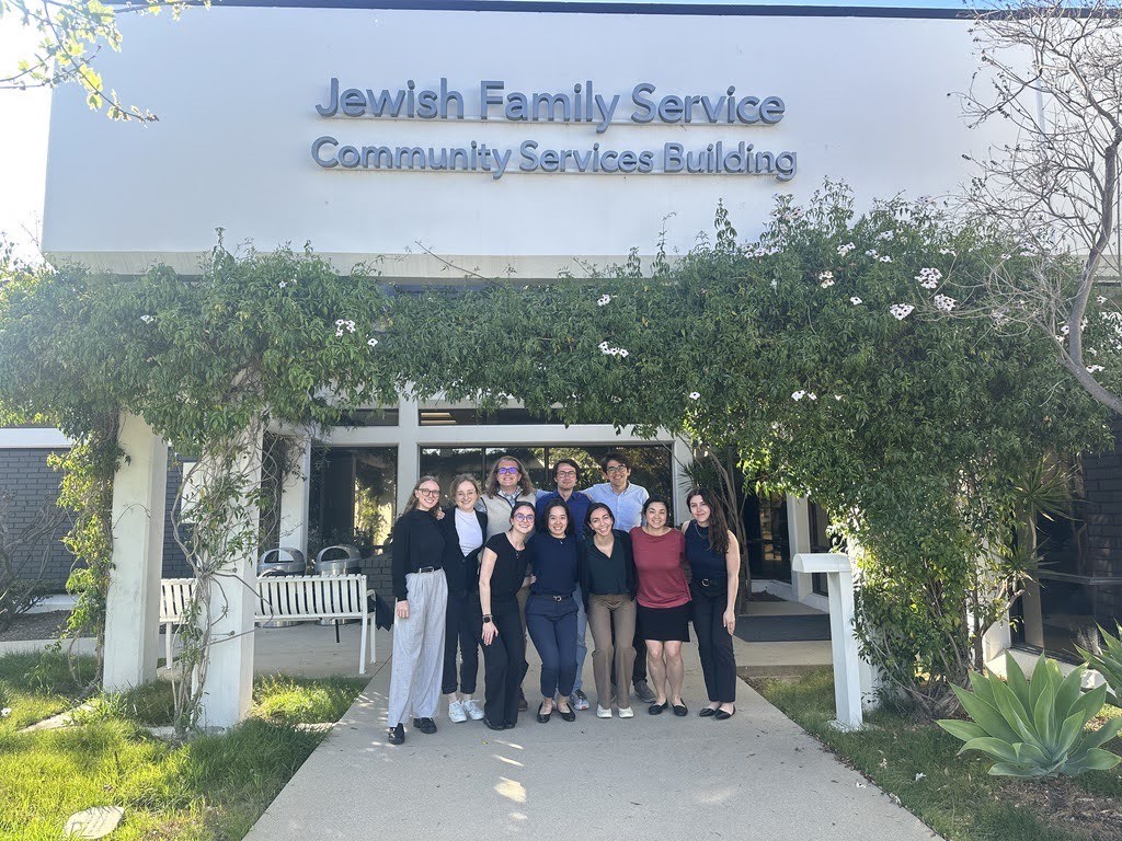 A group of students stands outside a sunny building