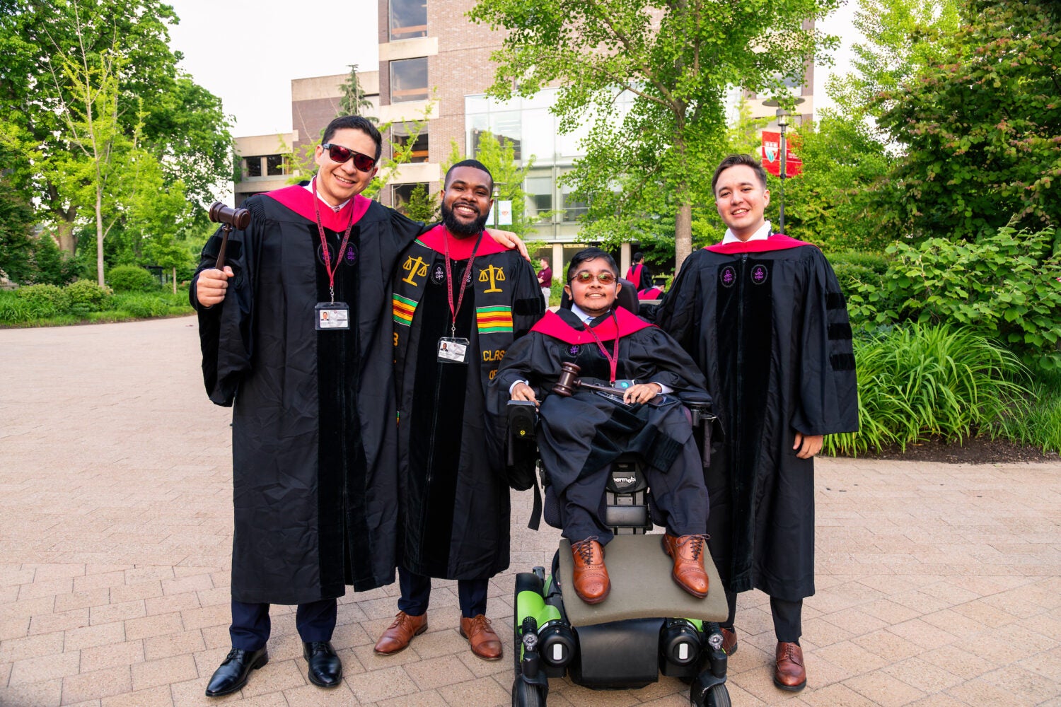 A group of HLS alumni in their graduation regalia smiling for a group photo