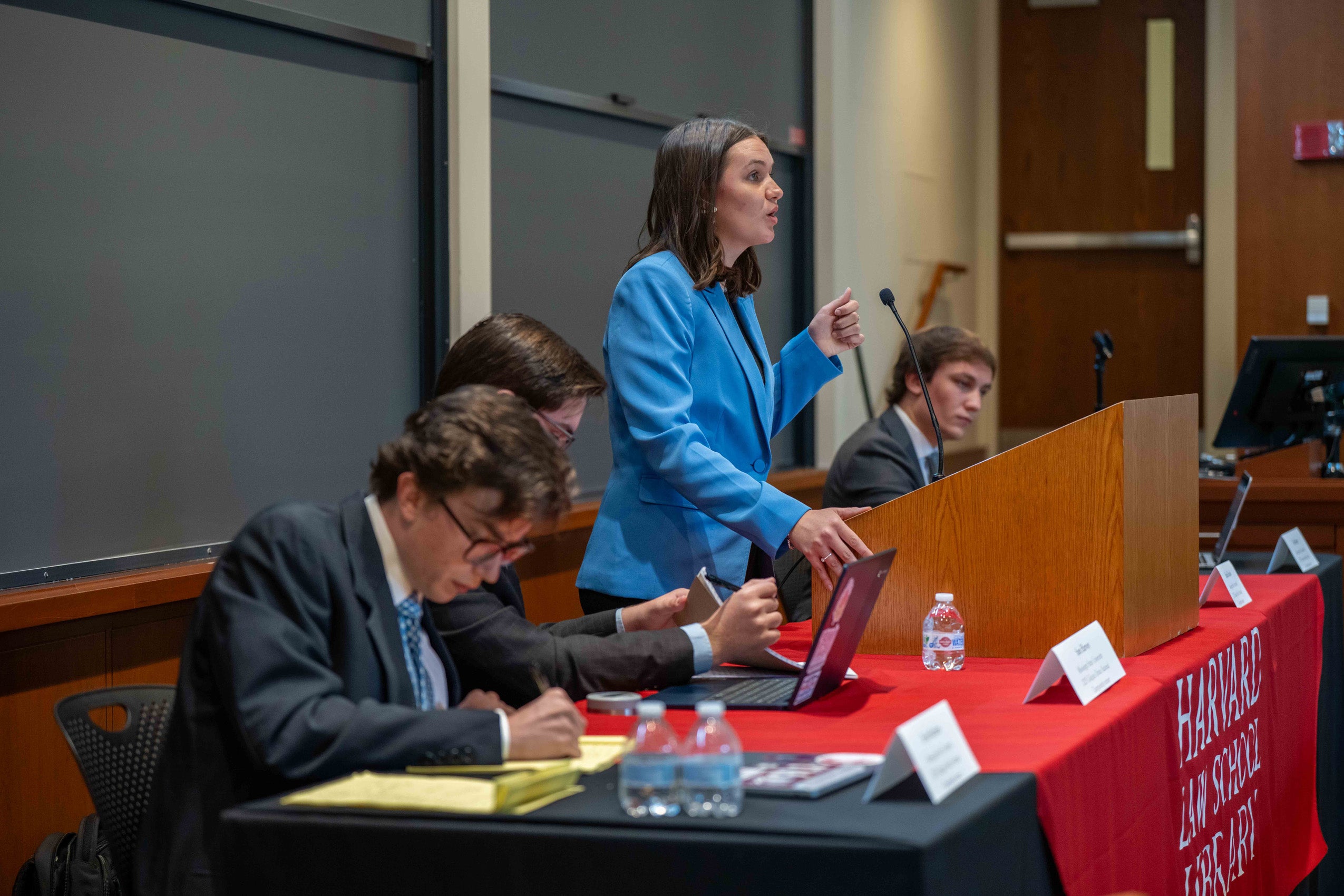 A woman at a podium speaks at a debate.