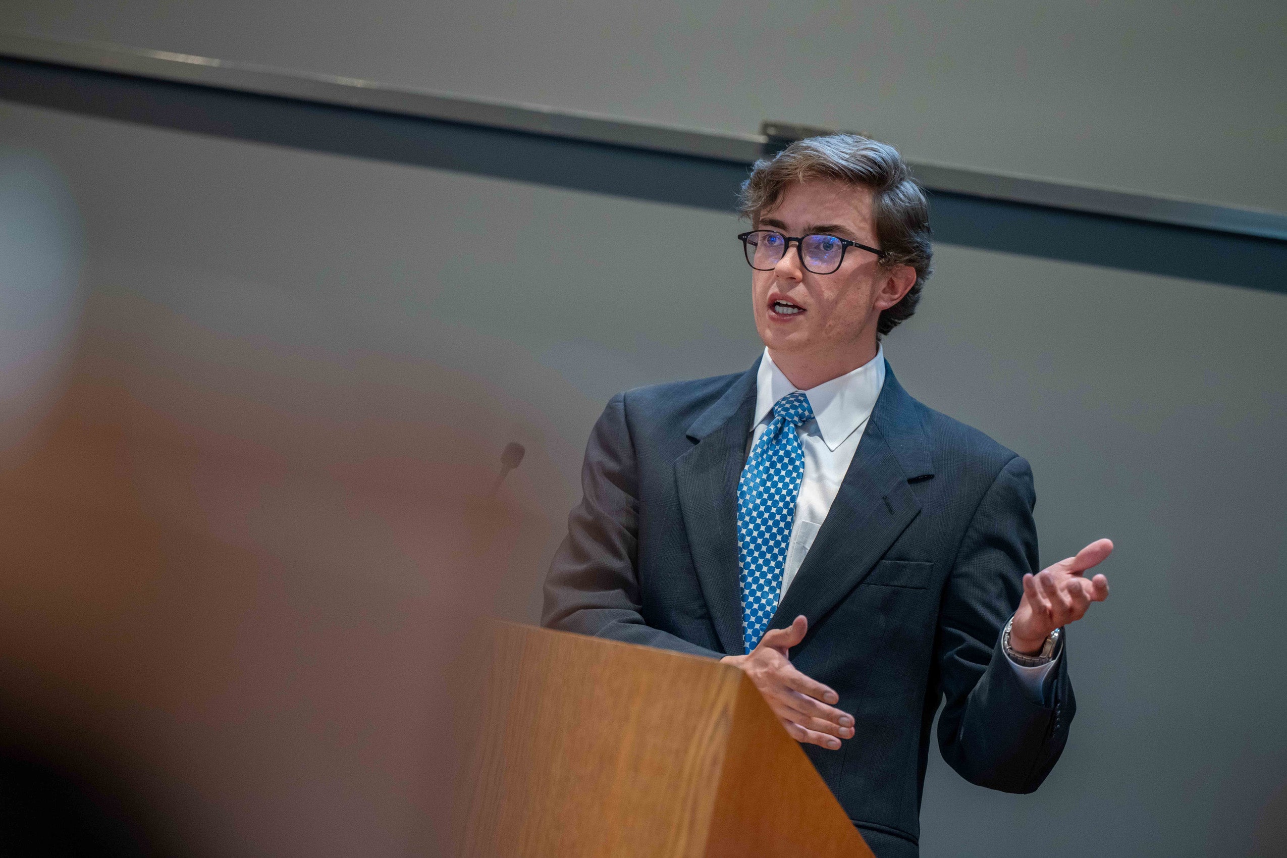 A students at a podium speaks as part of a mock debate.