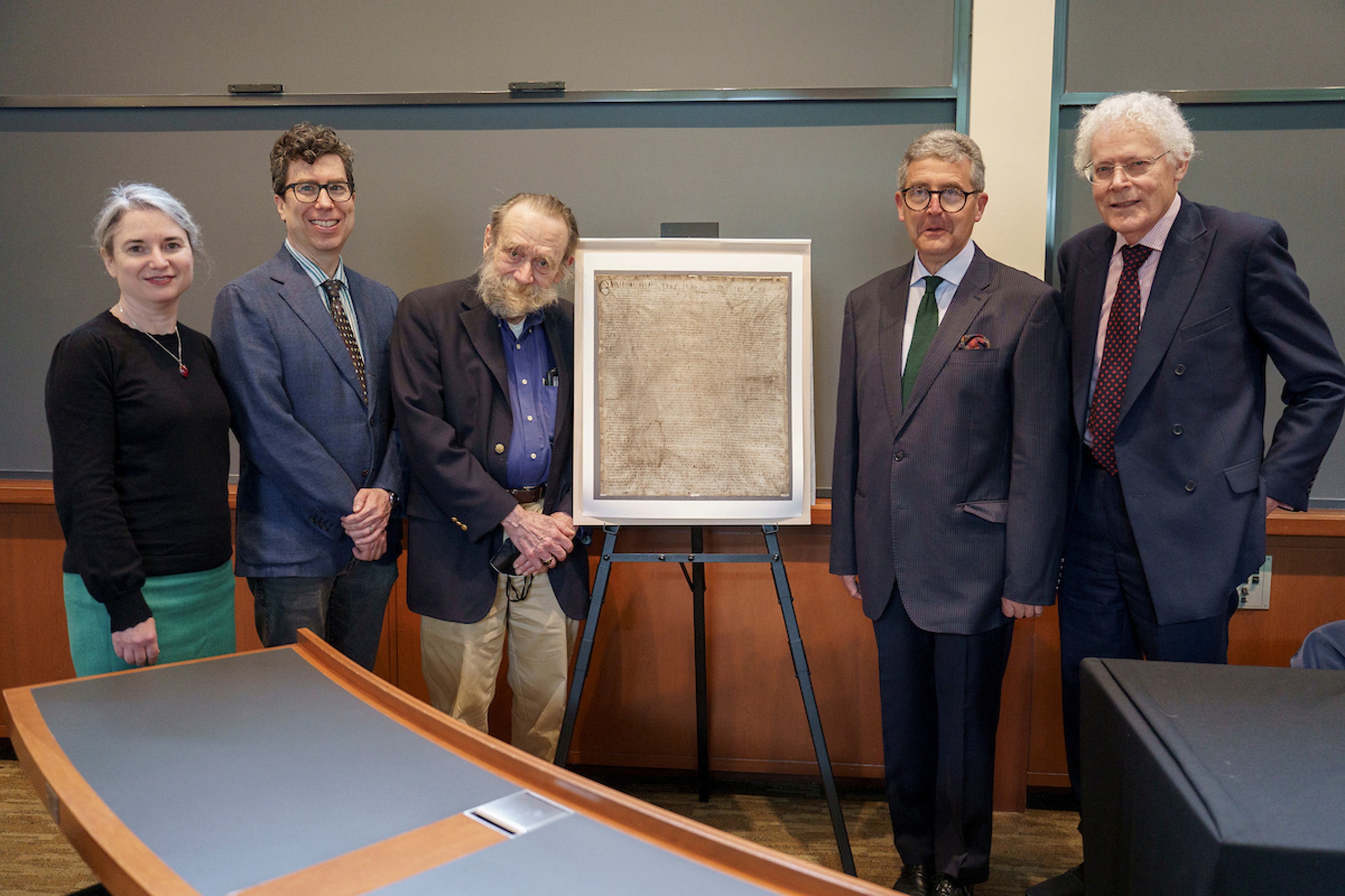 Panelists speaking on the Magna Carta pose with a copy of the document in a classroom.