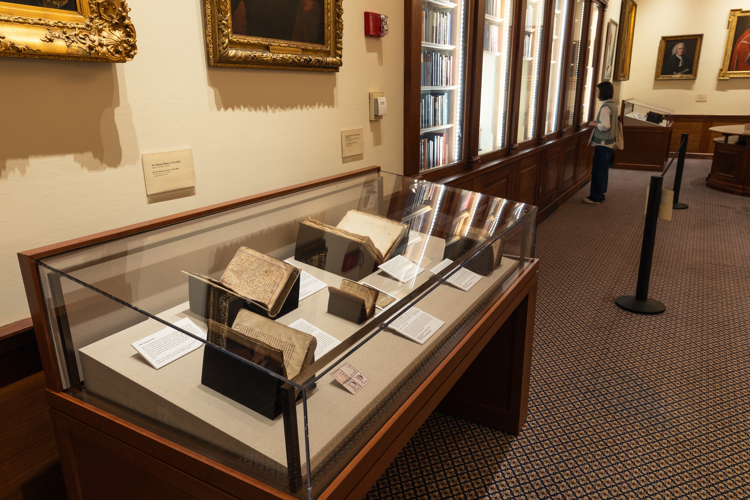 An overview of an Magna Carta exhibit in the Harvard Law School Library's Caspersen Room featuring a display case with various copies