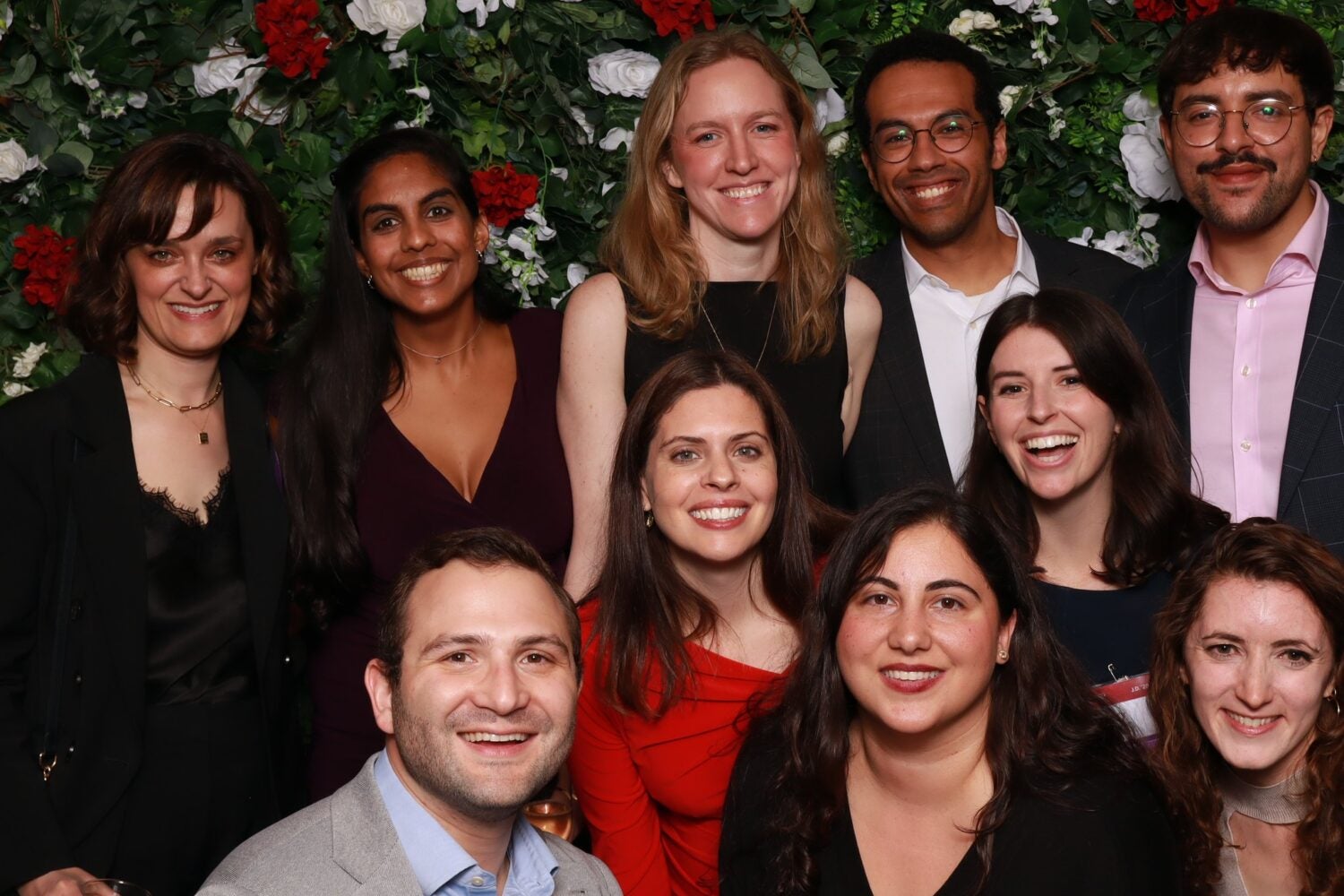 HLS alumni smiling for a group photo in front of a floral background