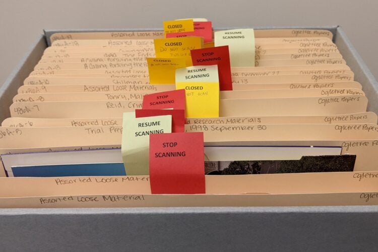 An open box containing 19 folders. Several flags are inserted into the folders with various typed phrases: “stop scanning,” “resume scanning,” and “closed.”