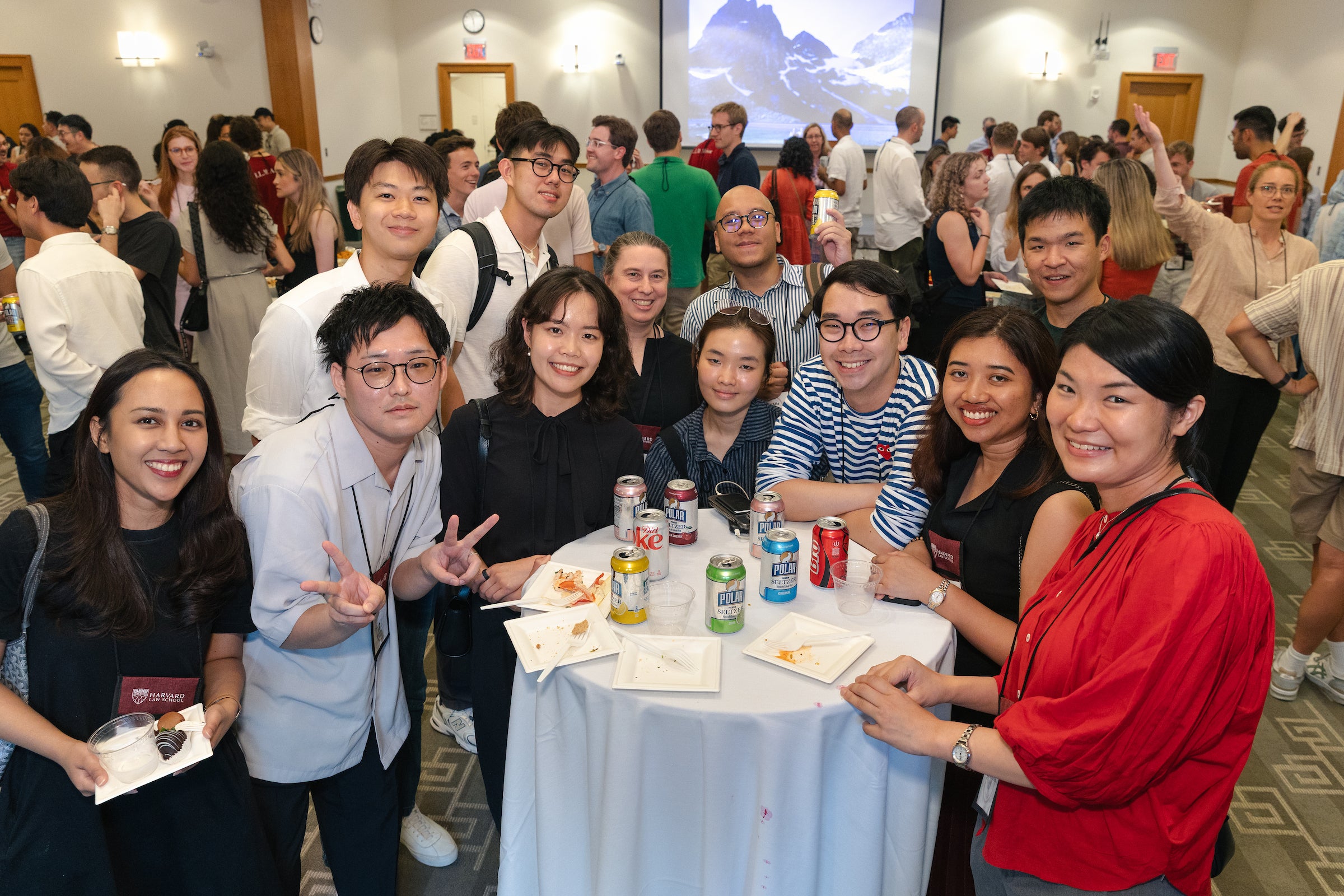 A large group poses around a table at an LL.M. welcome reception.
