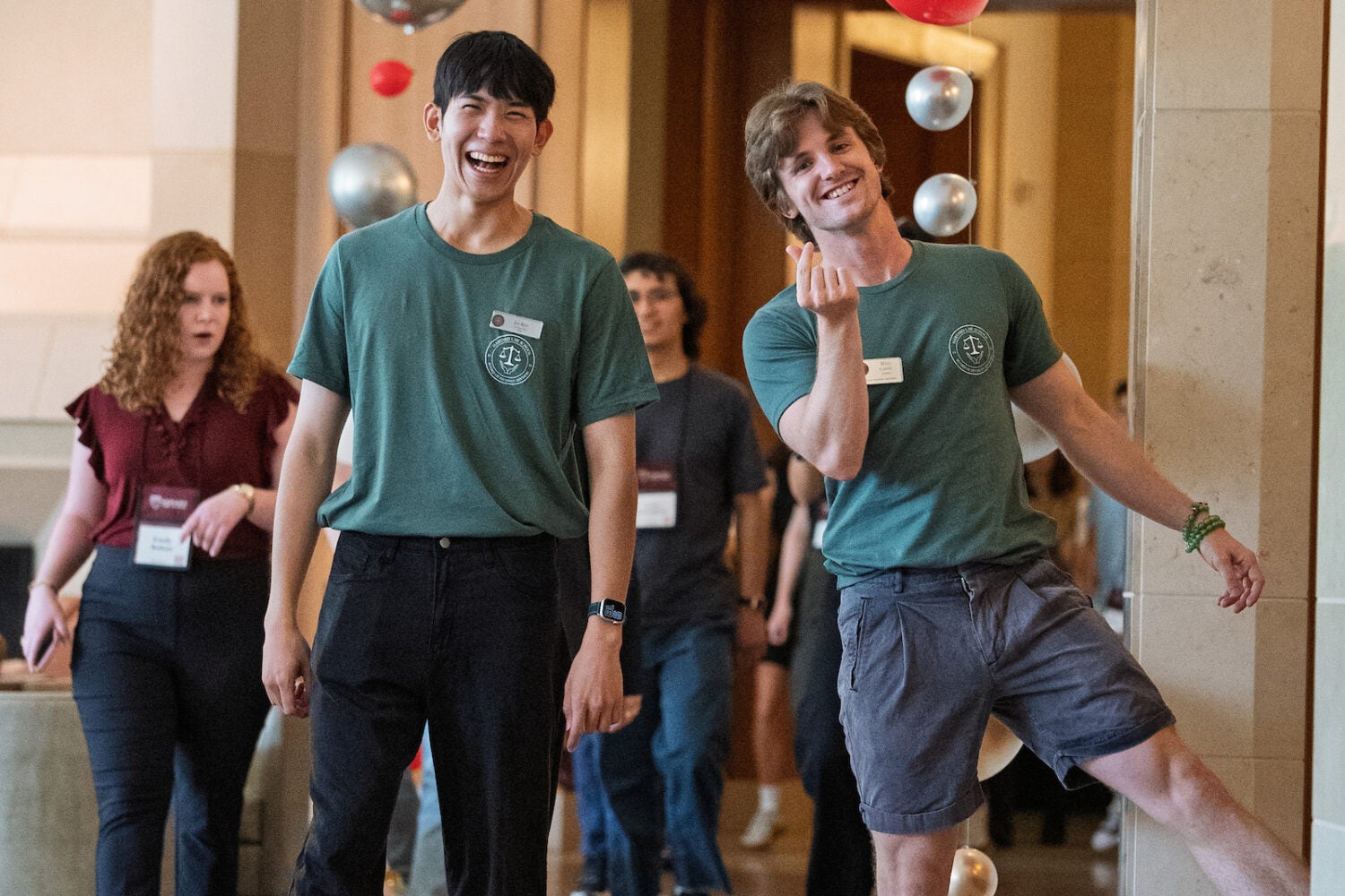 Two students walk together in a hallway in campus building decorated for orientation with balloons.