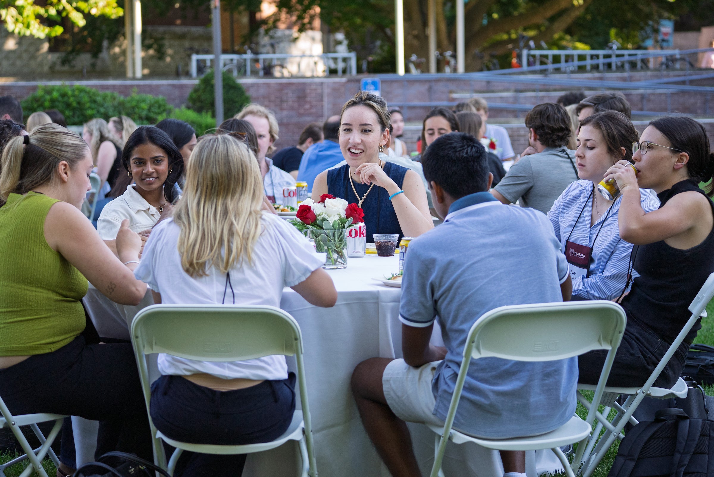 Groups of students meet around tables outside on campus.