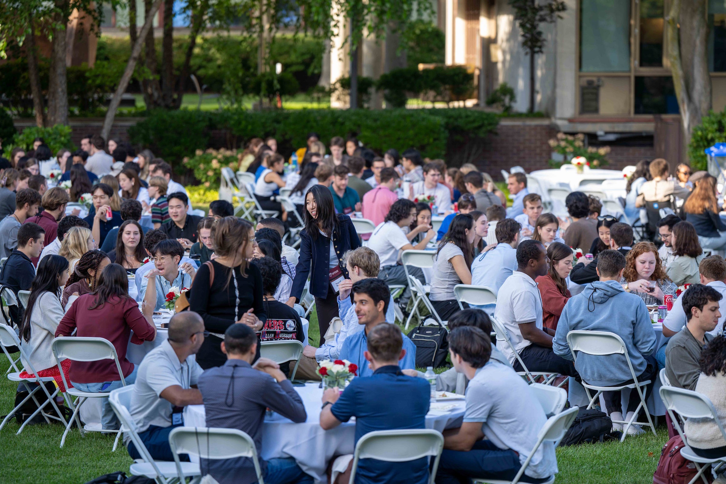 Groups of students sitting outside around round tables at an event.
