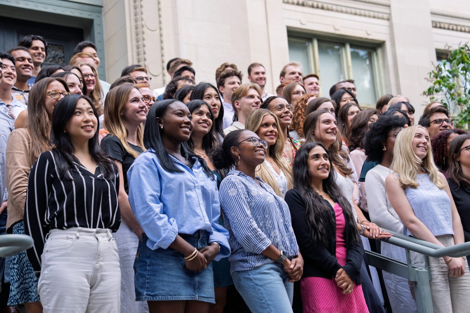 A large group of students pose on the steps of a building.