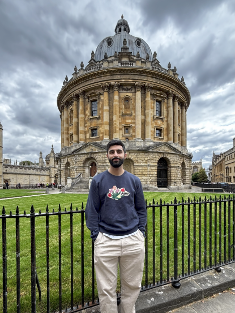 Man poses outside cylindrical building.