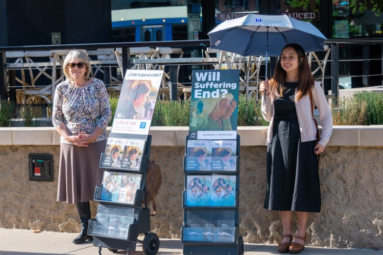 Two women standing next to pamphlet displays.