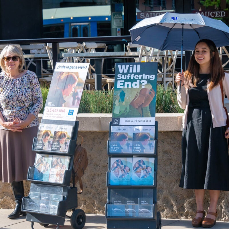 Two women standing next to pamphlet displays.