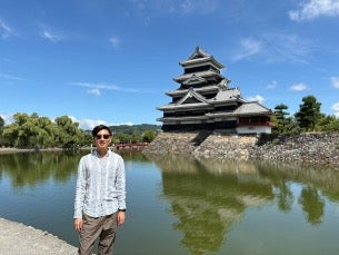 Man poses outside the Matsumoto Castle.