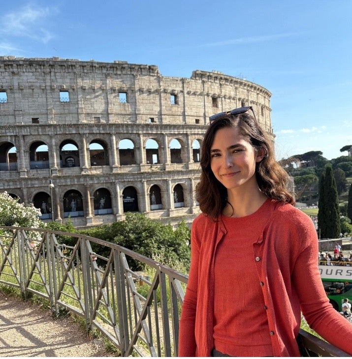 Woman standing outside Colosseum in Italy.