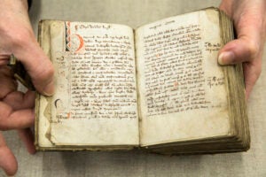 A hand holding open the pages of an old book.