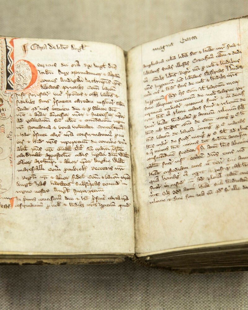 A hand holding open the pages of an old book.