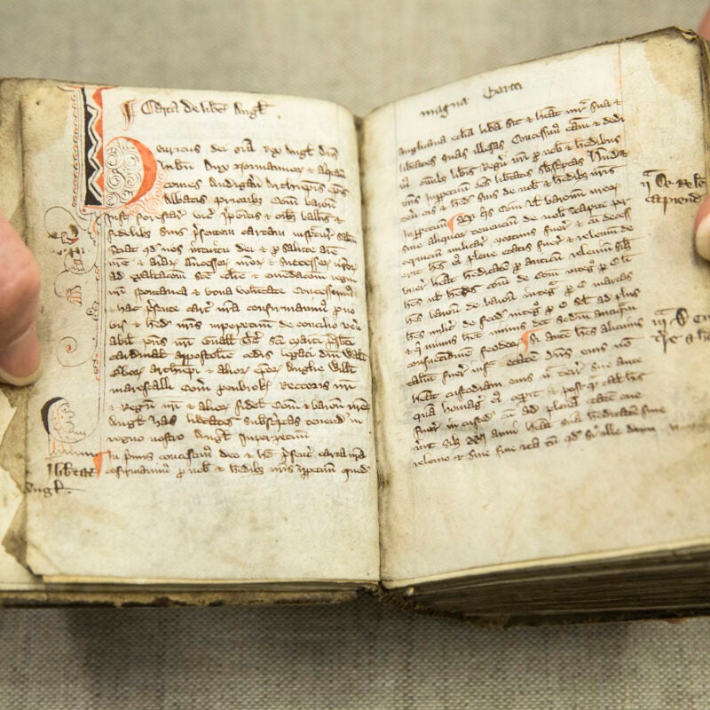 A hand holding open the pages of an old book.