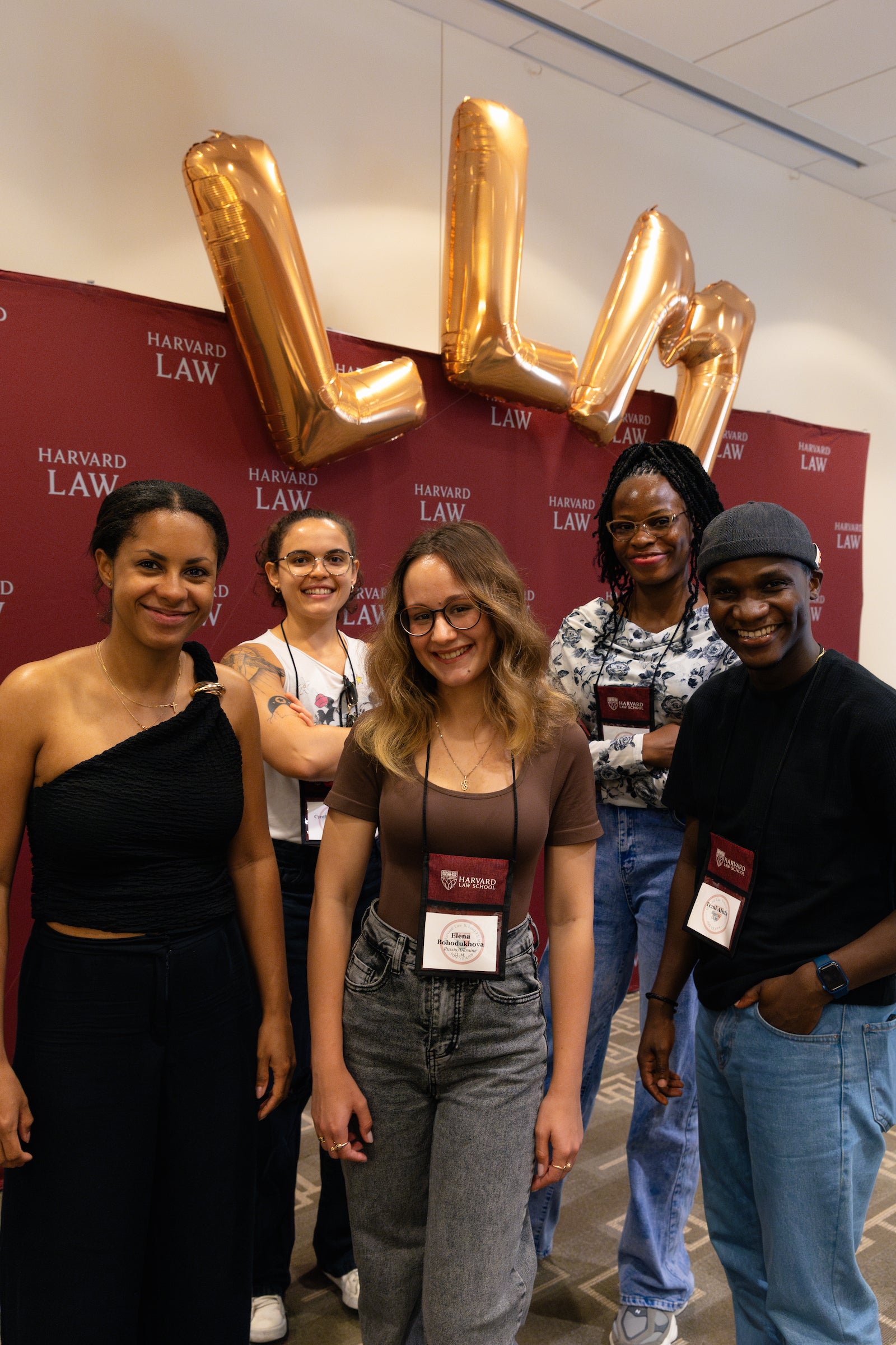 Group of students stand under LL.M. ballons during orientation.
