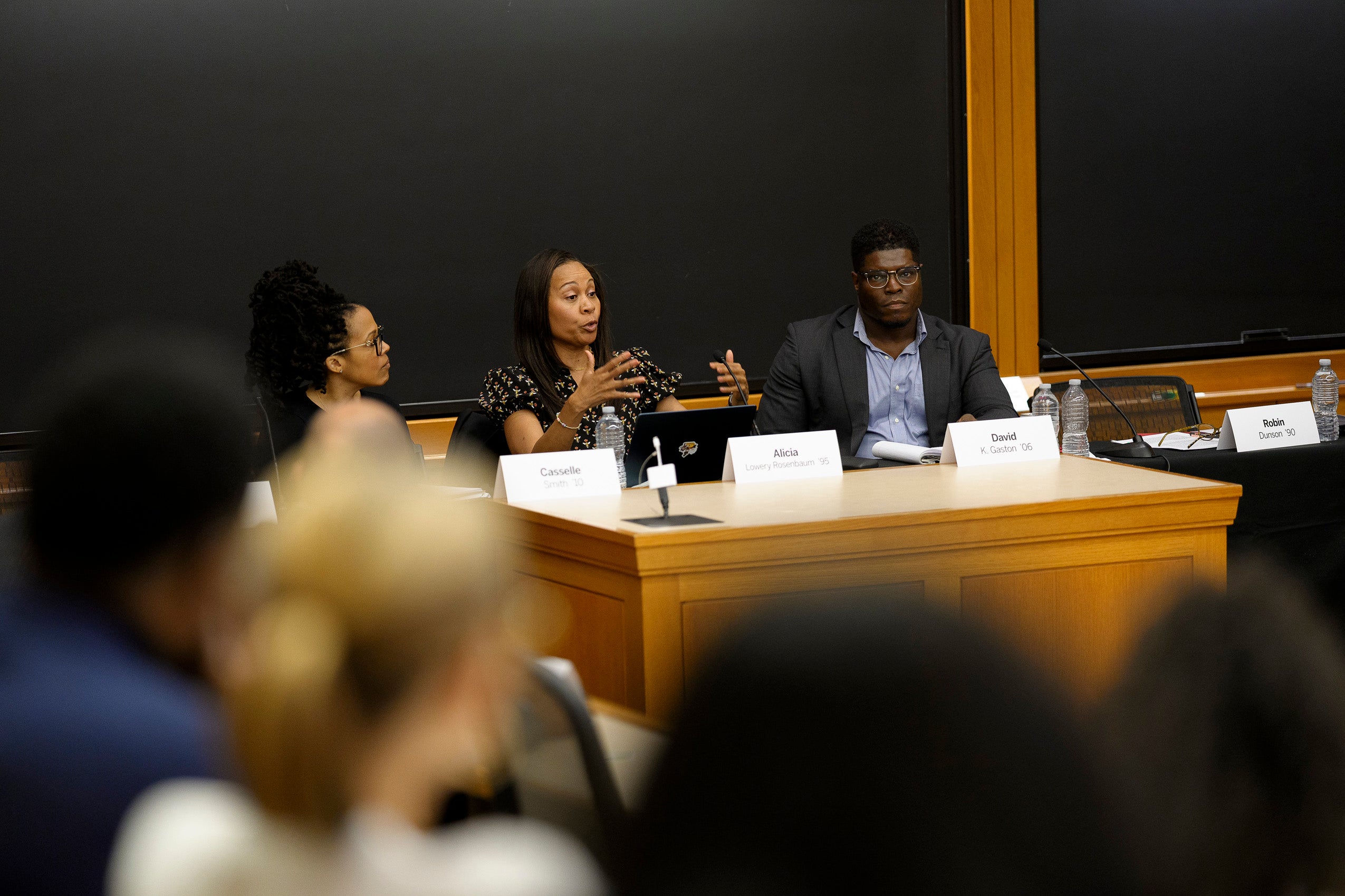 Three people speaking on a panel in a classroom.