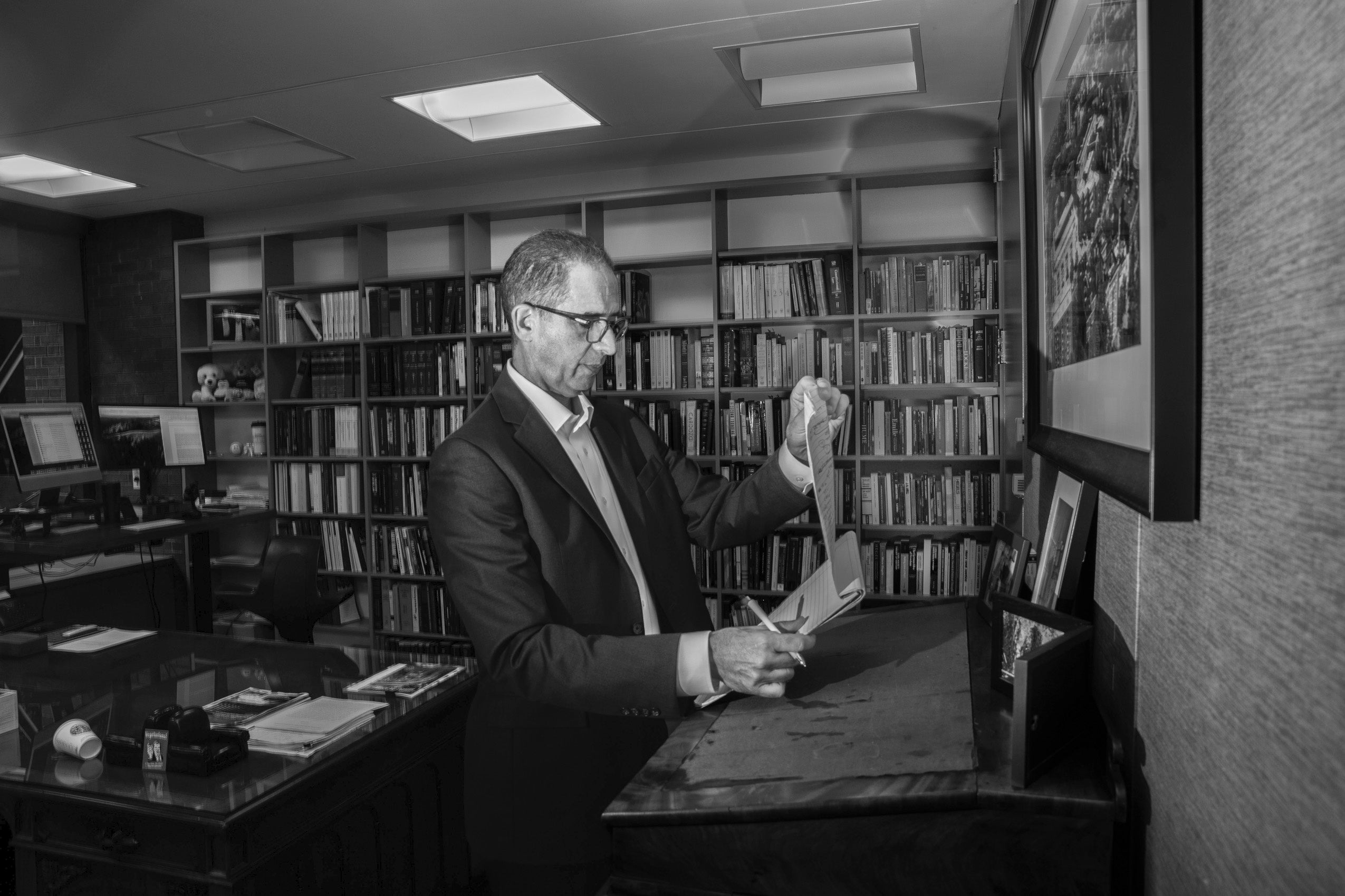 John Goldberg standing at a desk looking at papers.