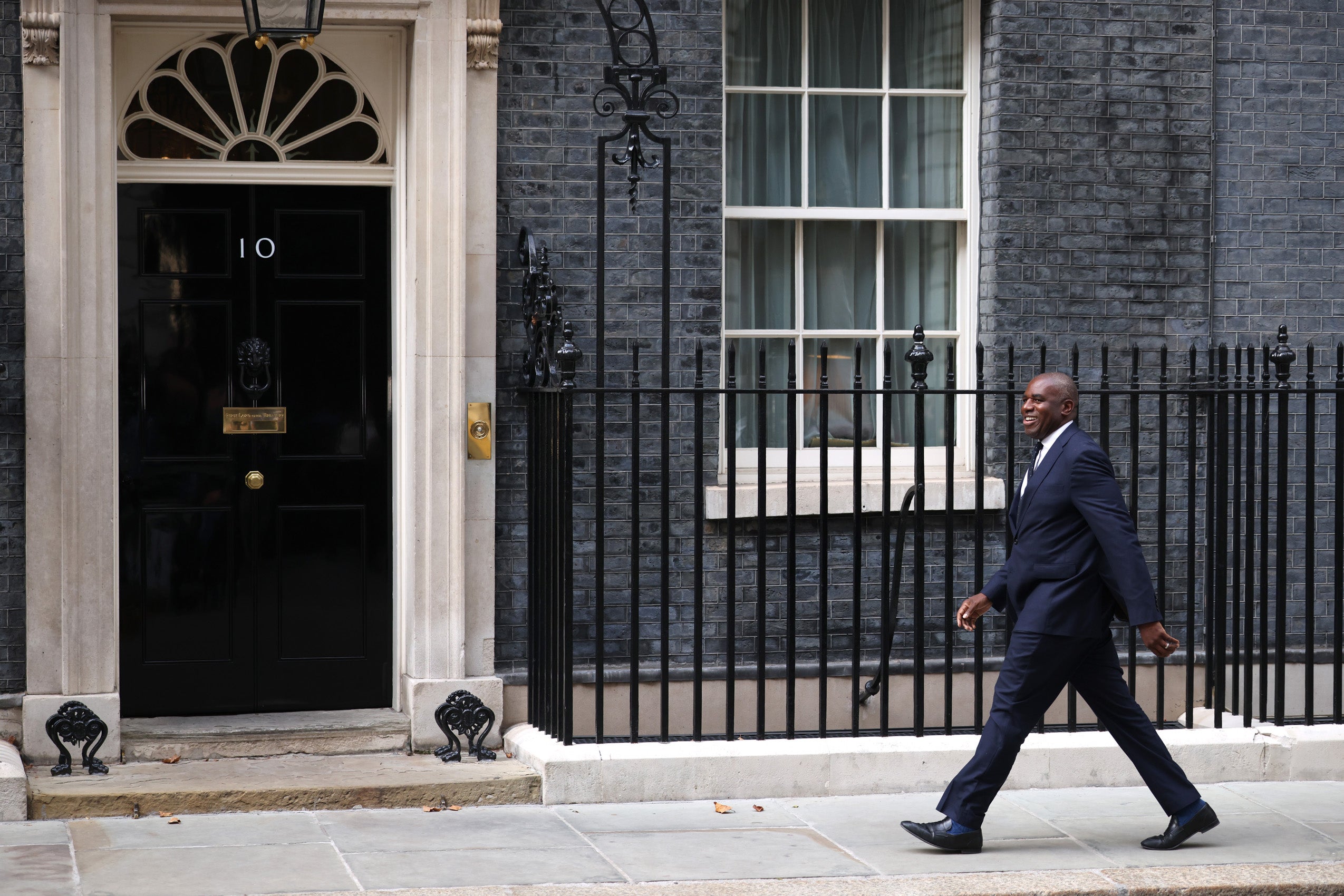 David Lammy walking in front of a building