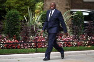 David Lammy walking on a path lined with flowers.