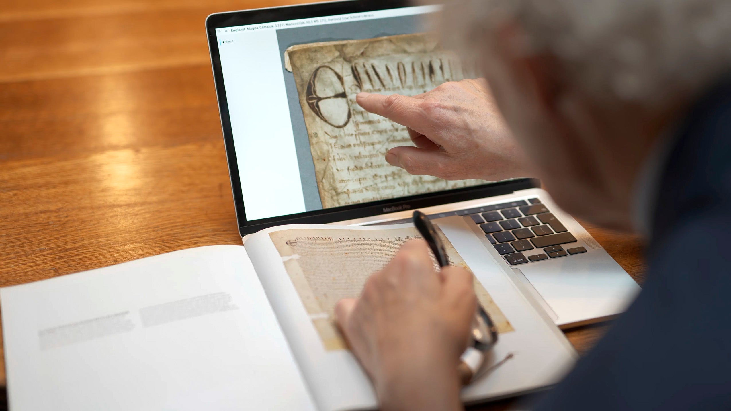 A man pointing to a computer that has a manuscript on the screen.
