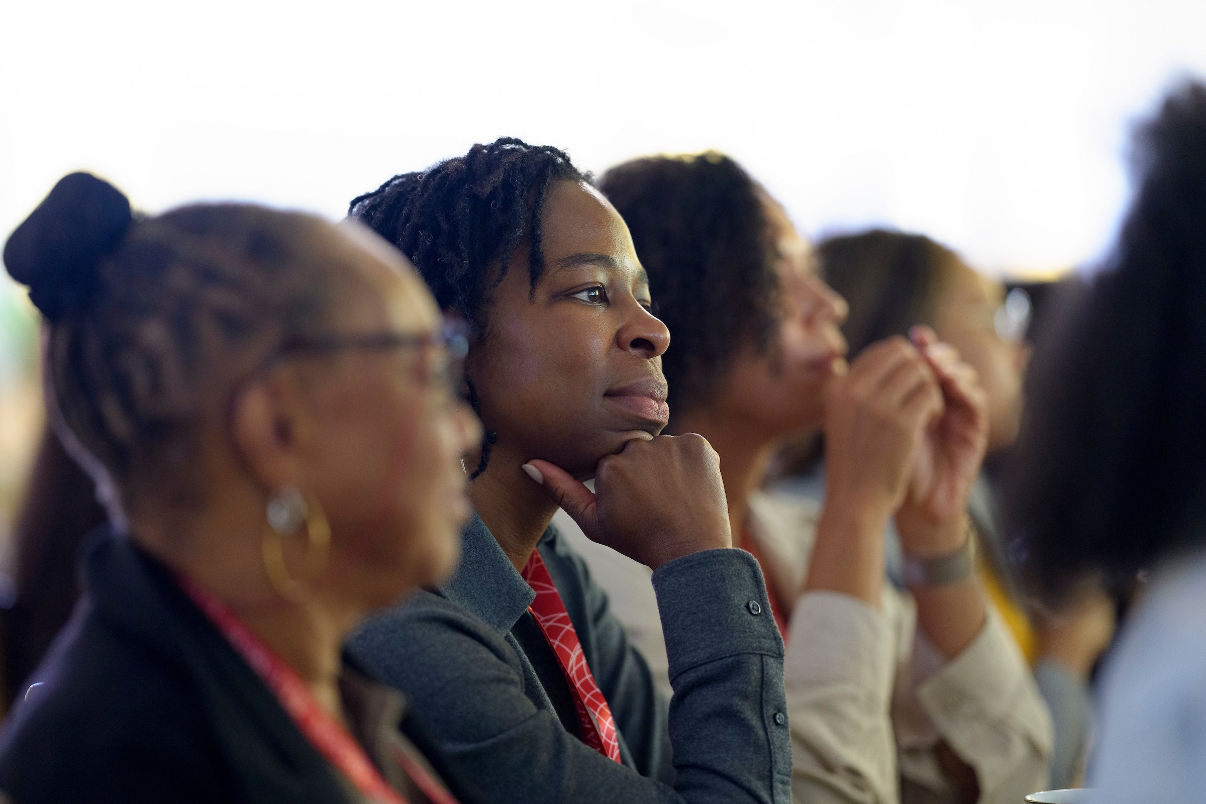 A close up of a row of people listening to a speaker at an event.