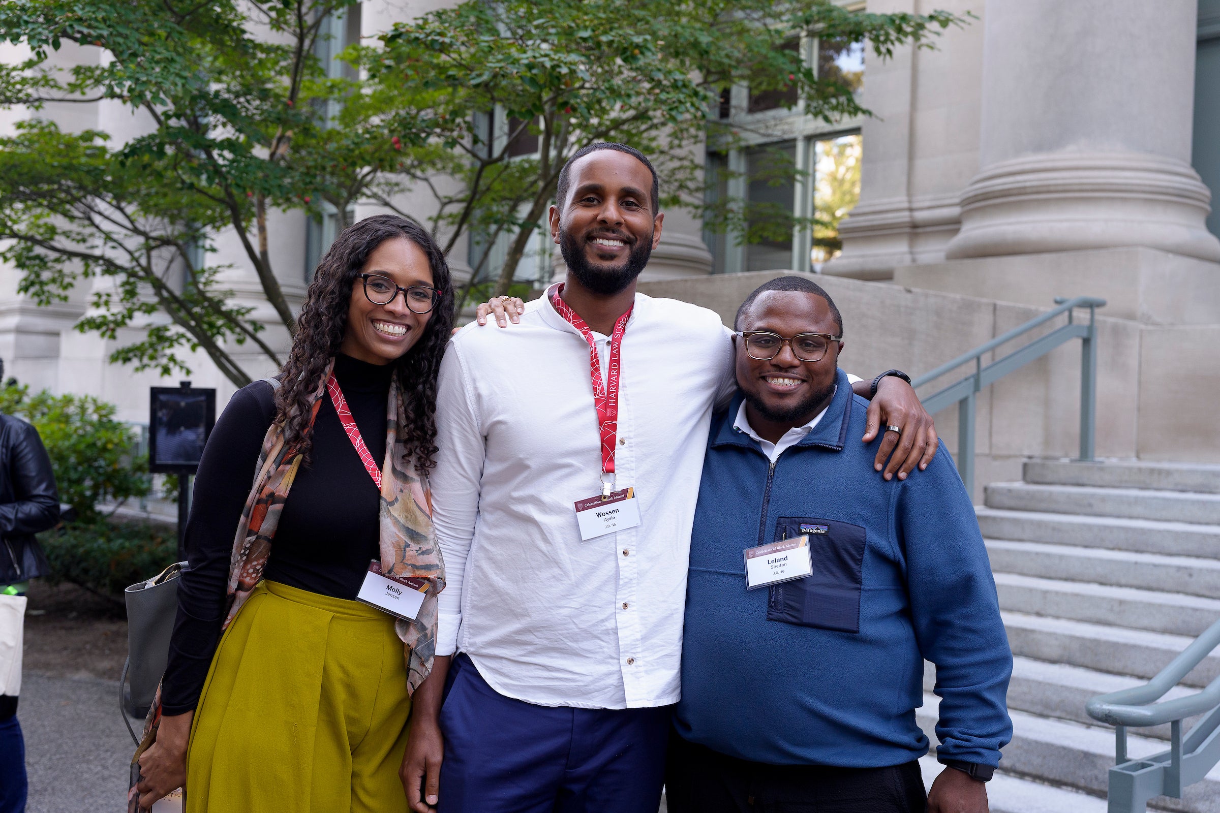 Three people pose for a photo outside on campus.