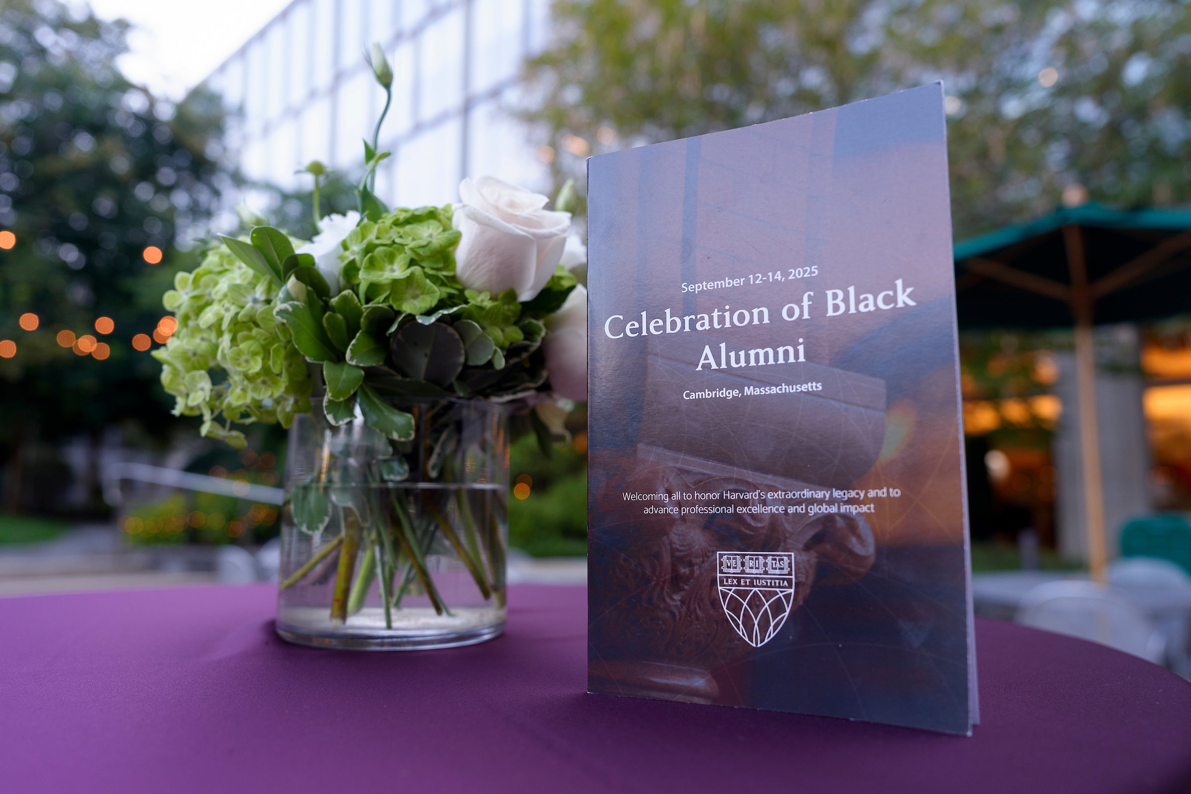 A vase of flowers and program for the Celebration of Black Alumni on a table.