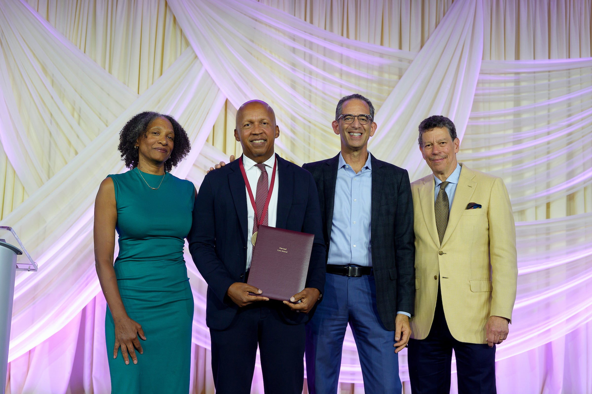A group of 4 people posing for a photo with Bryan Stevenson holding an award.