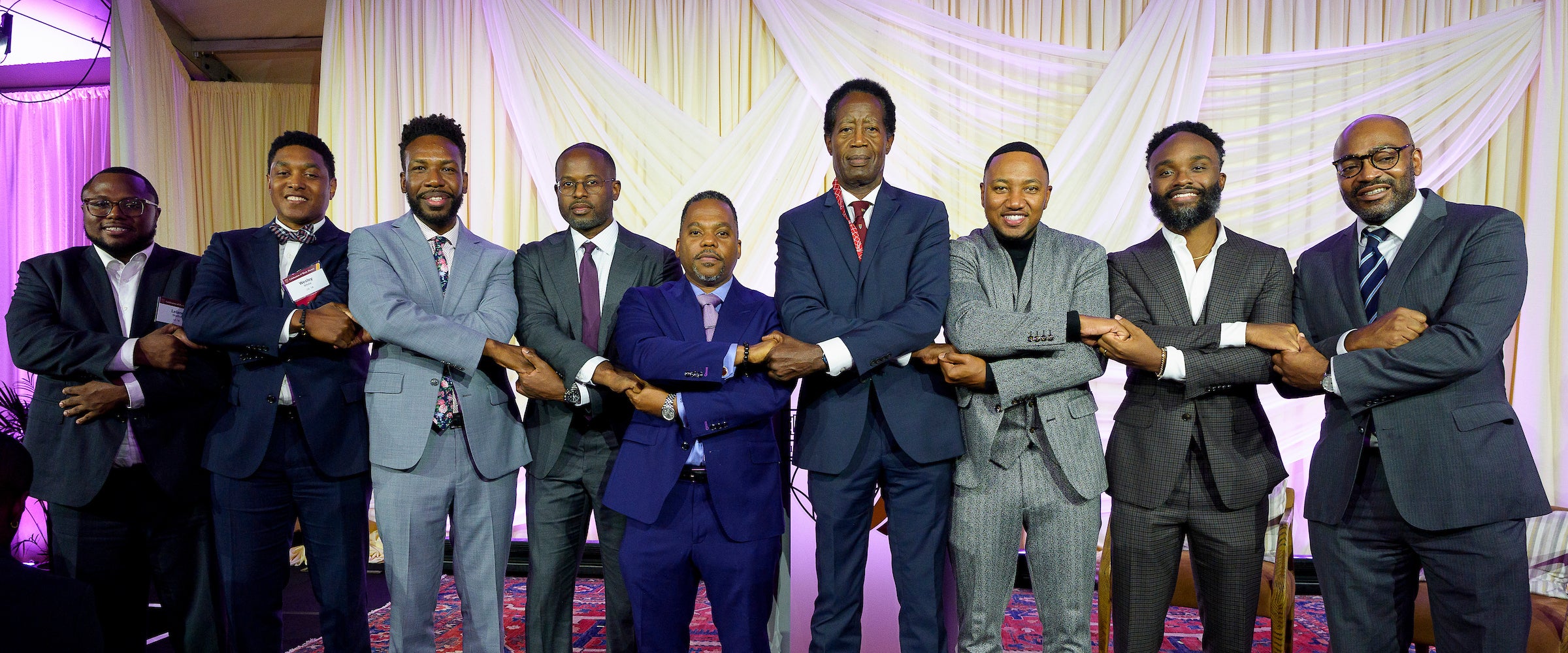 A group of men arms crossed pose at an event.