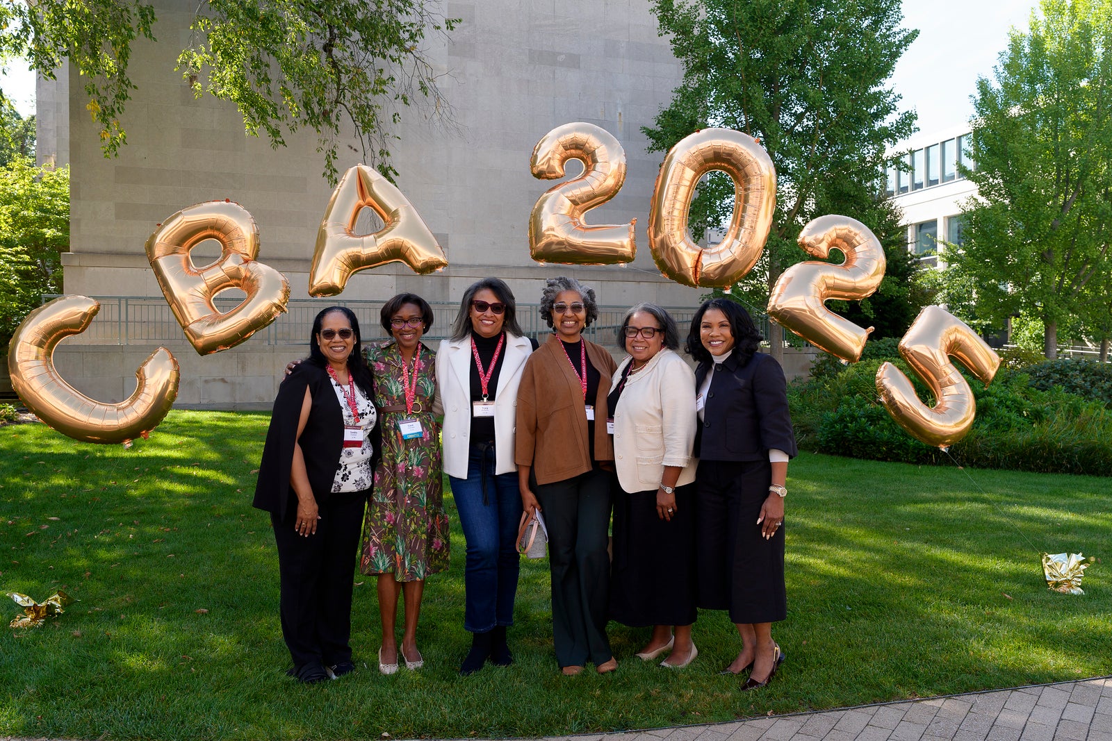 A group of HLS alumni standing under an arch of gold balloons that spell out