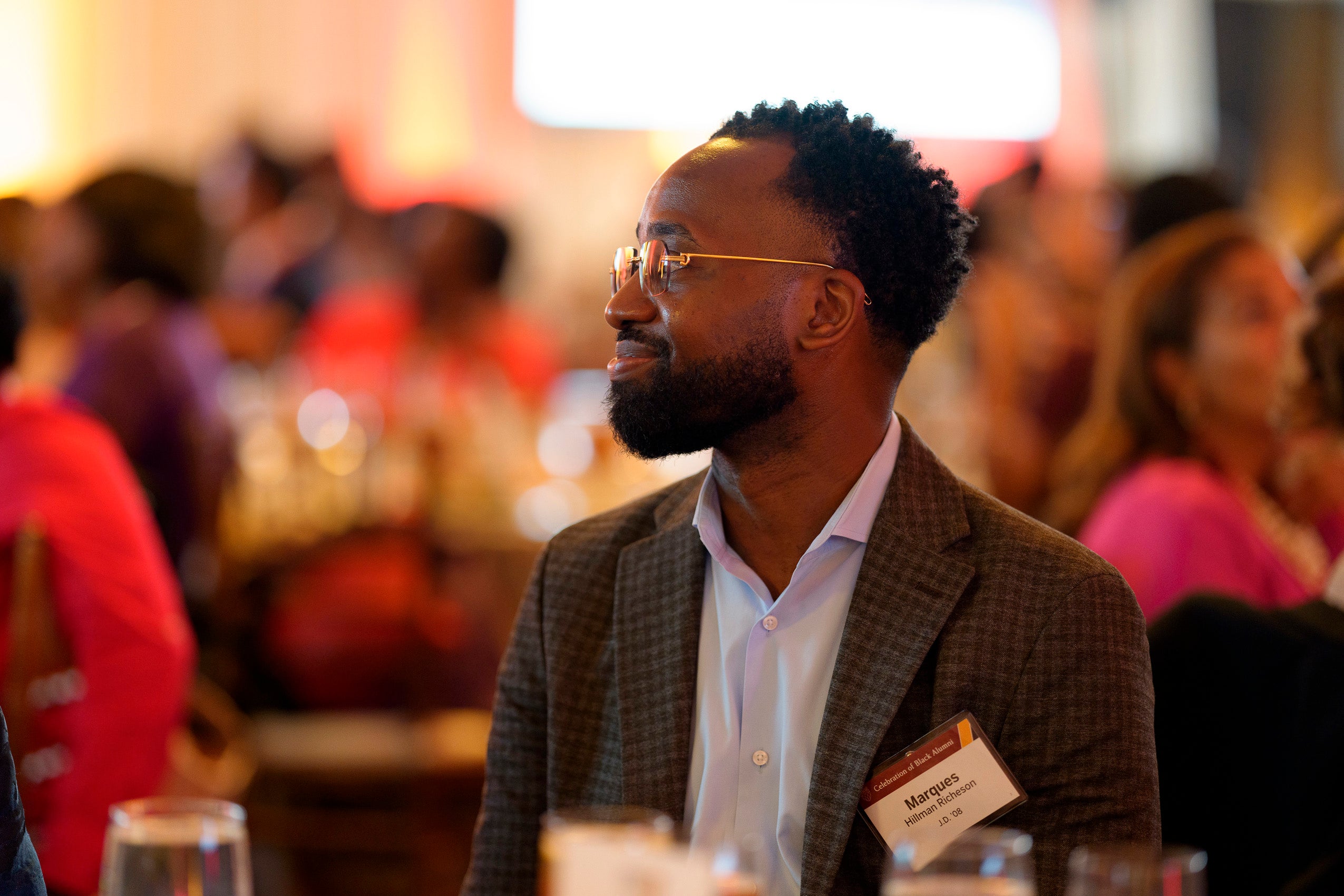 A man at a table listens to a speaker.