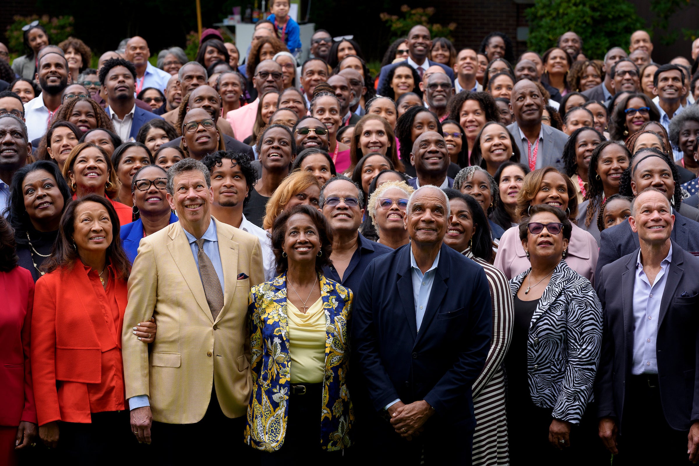 A large group of people pose for a group photo on a field.