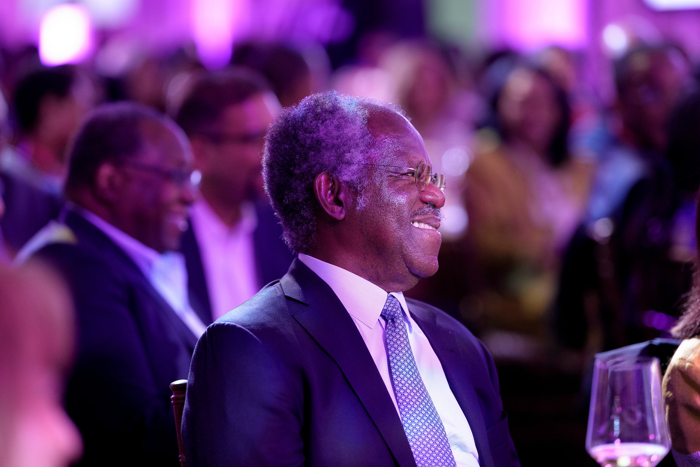 A close up of a man smiling in the audience at an event.