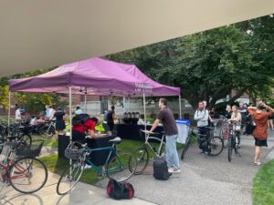 Students with bikes line up at a tent.