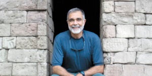 John Leshy sitting in a opening in a stone wall.