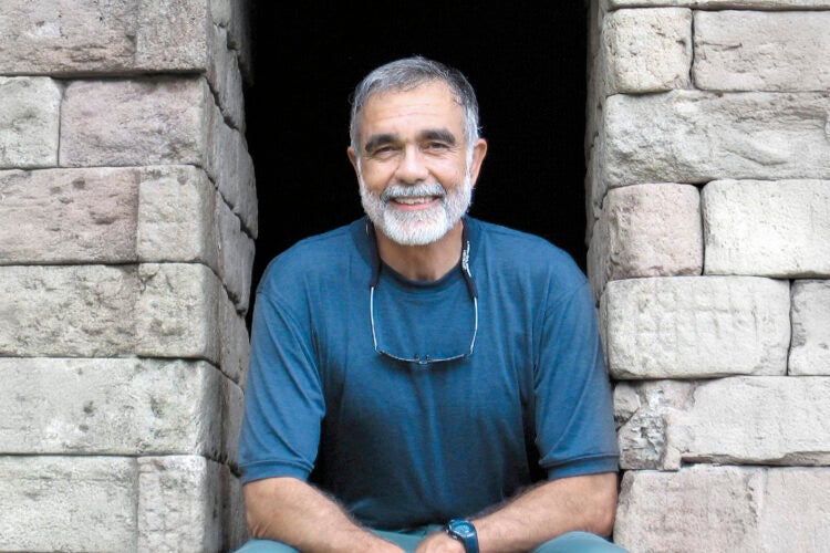 John Leshy sitting in a opening in a stone wall.