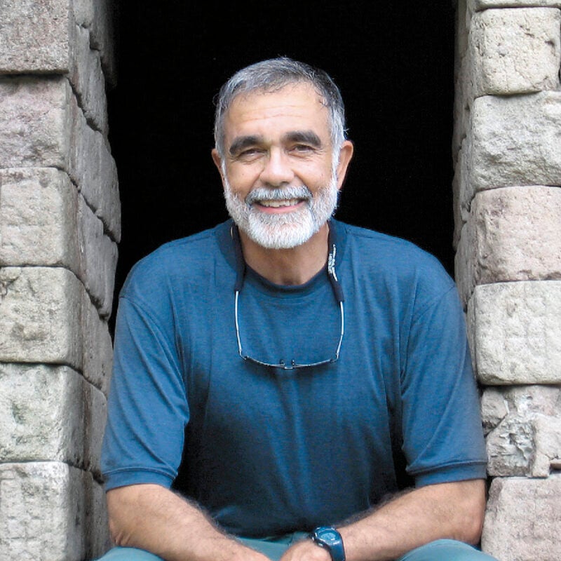 John Leshy sitting in a opening in a stone wall.