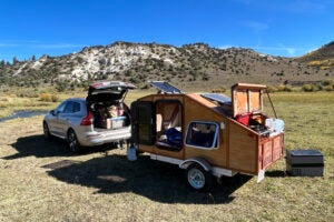 A car with a custom built wooden trailer attached.