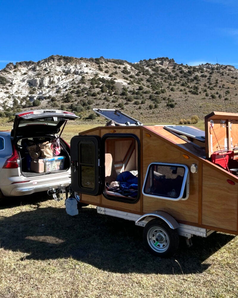 A car with a custom built wooden trailer attached.