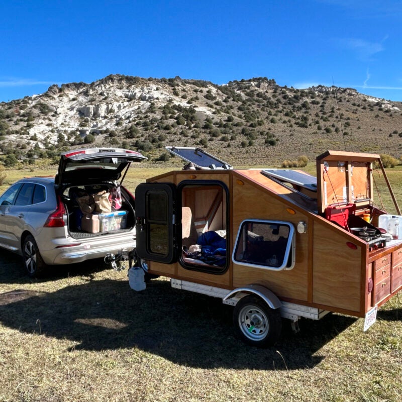 A car with a custom built wooden trailer attached.