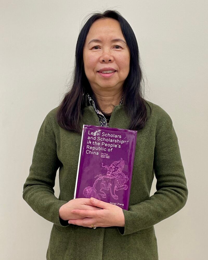 Librarian Nongji Zhang holding the book she wrote, Legal Scholars and Scholarship in the People’s Republic of China: The First Generation, 1949–1992.