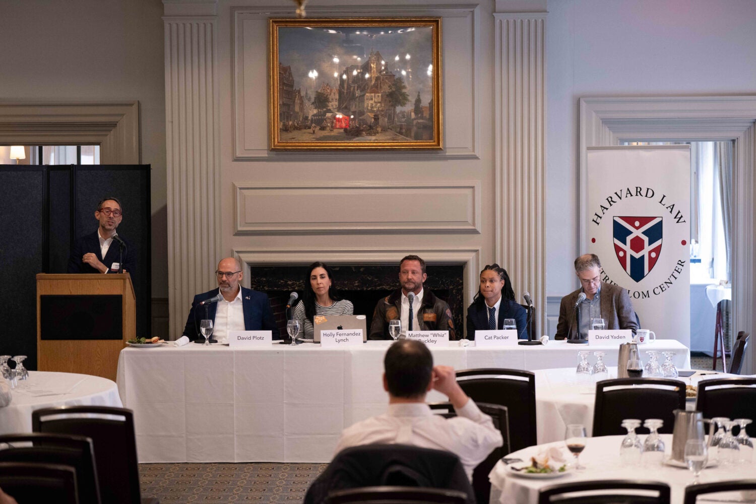 Glenn Cohen delivers remarks at a podium next to seated panelists.