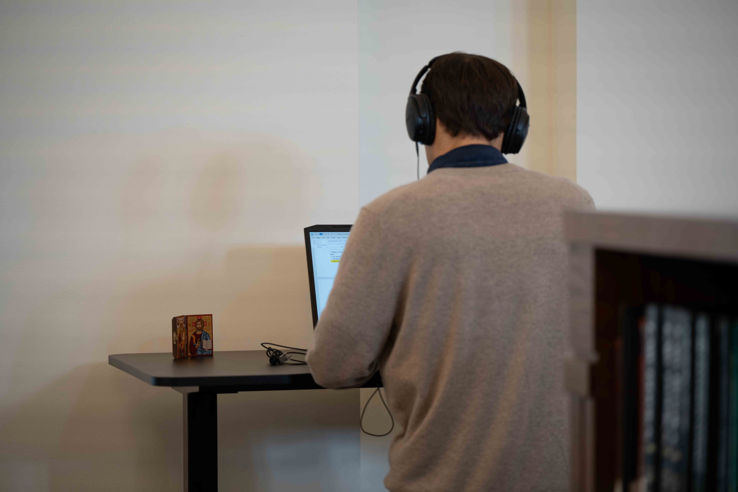 A student works at a desk while wearing headphones.